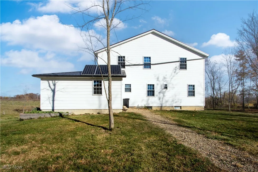 Rear view of house featuring solar panels and a yard