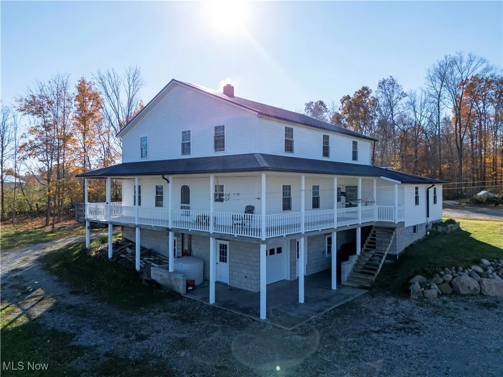 Back of property featuring a large porch, a metal roof, stairs, and a chimney