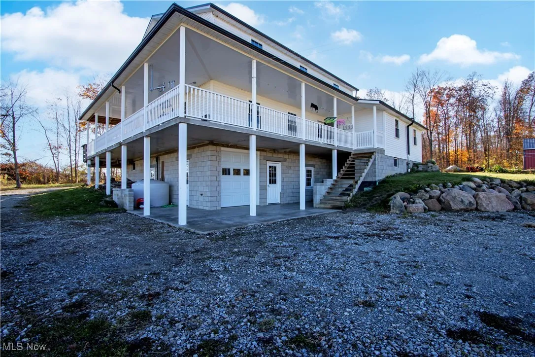 View of side of property featuring an attached garage, a patio area, driveway, stairs, and a wooden deck