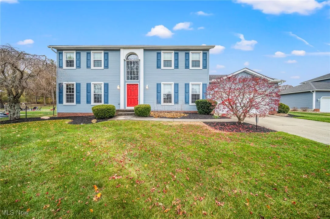 Colonial house with concrete driveway and a front lawn