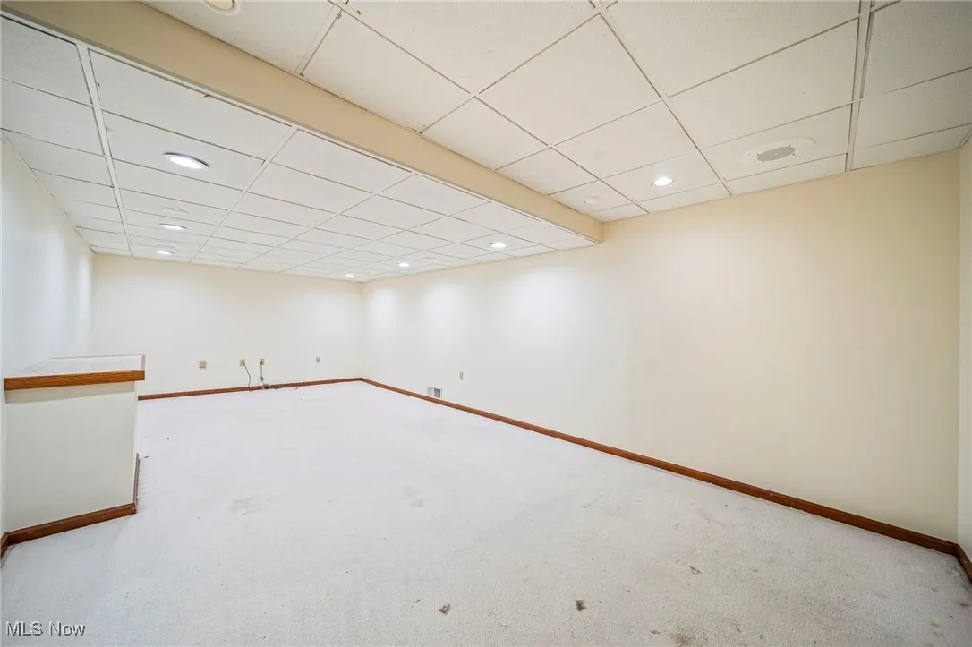 Finished below grade area featuring a drop ceiling, carpet flooring, and recessed lighting