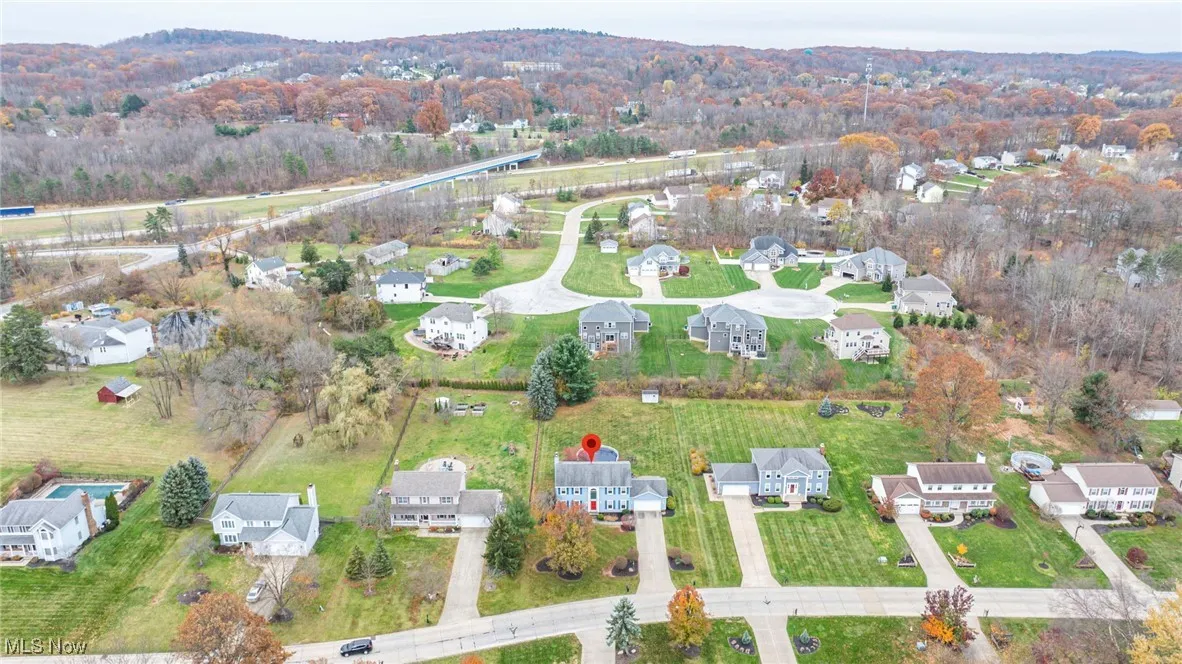Aerial overview of property's location featuring nearby suburban area and a forest