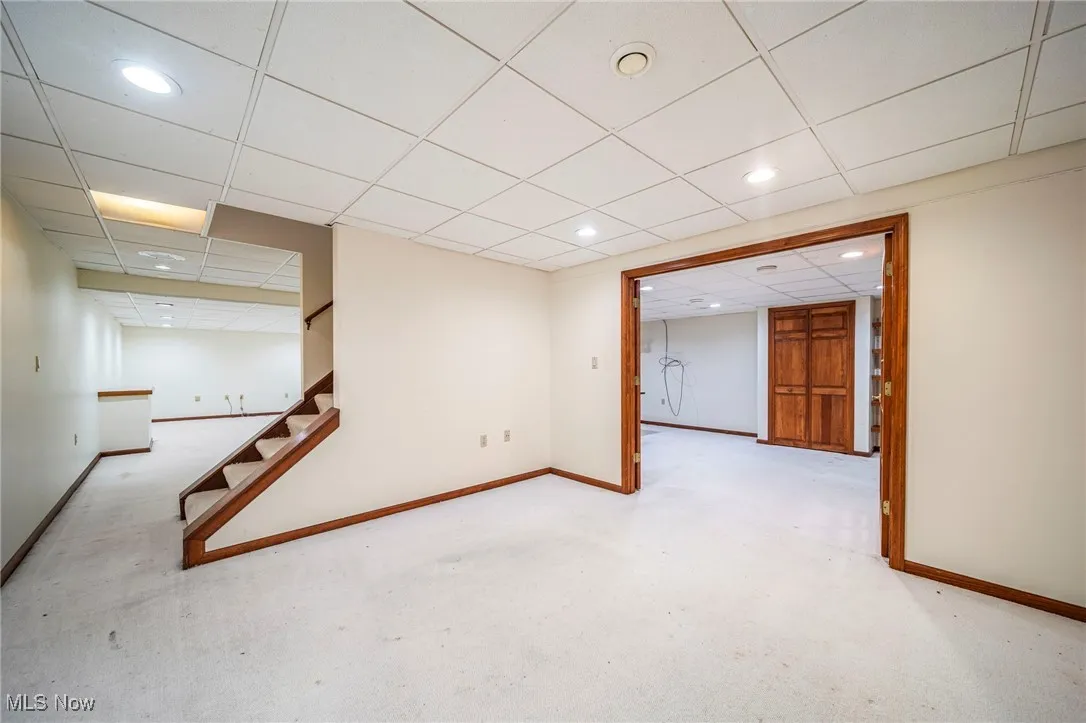 Finished basement with carpet flooring, a drop ceiling, recessed lighting, and stairs