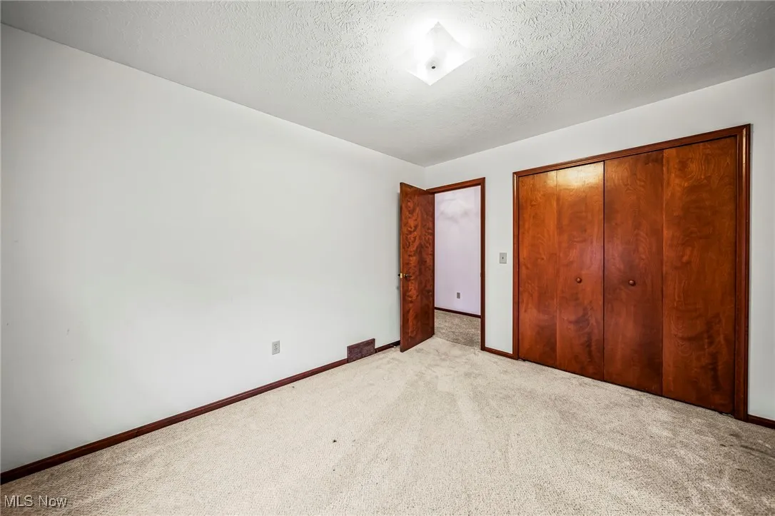 Unfurnished bedroom featuring carpet, a closet, and a textured ceiling