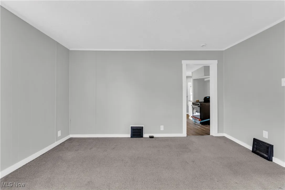Carpeted spare room with crown molding