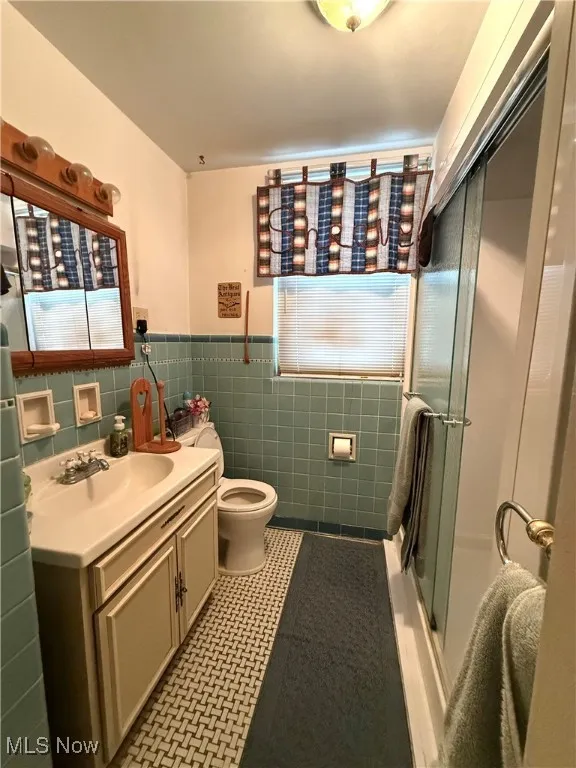 Bathroom with vanity, tile walls, a wainscoted wall, and light tile patterned flooring