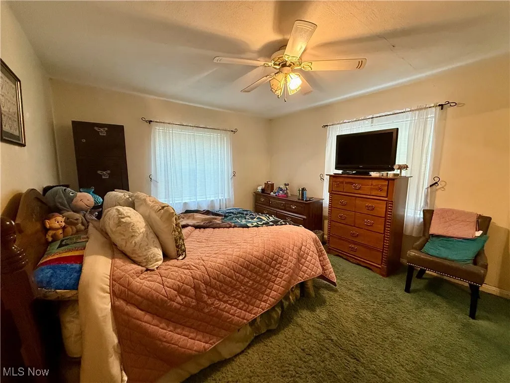 Carpeted bedroom featuring a ceiling fan