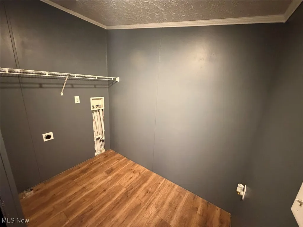 Washroom featuring crown molding, wood finished floors, a textured ceiling, hookup for a washing machine, and electric dryer hookup