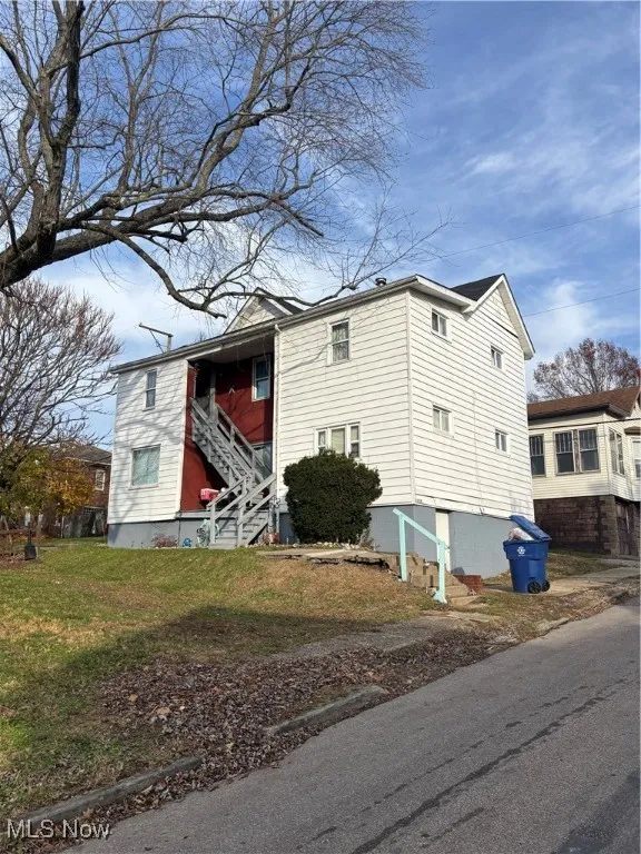 View of front of property with stairs and a front yard