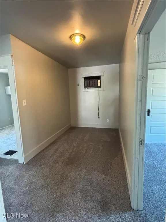 Empty room with dark carpet and a wall unit AC