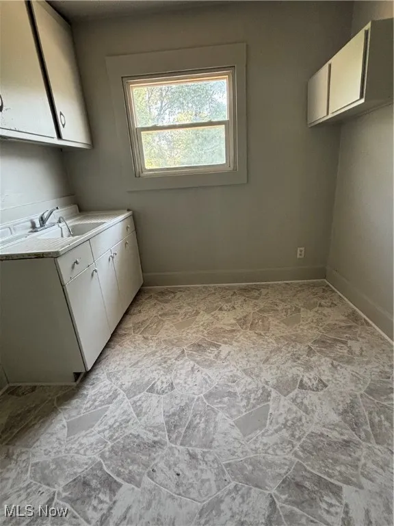Laundry area featuring cabinet space and light stone finish floors