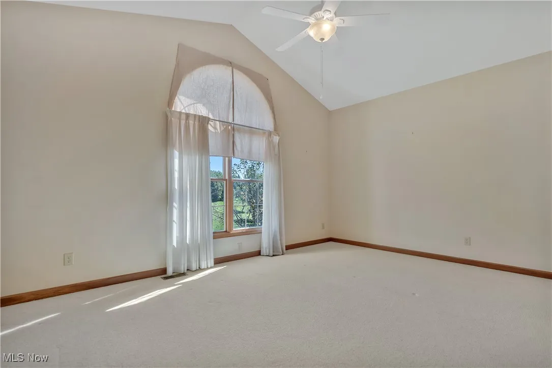 2nd bedroom featuring high vaulted ceiling and a ceiling fan