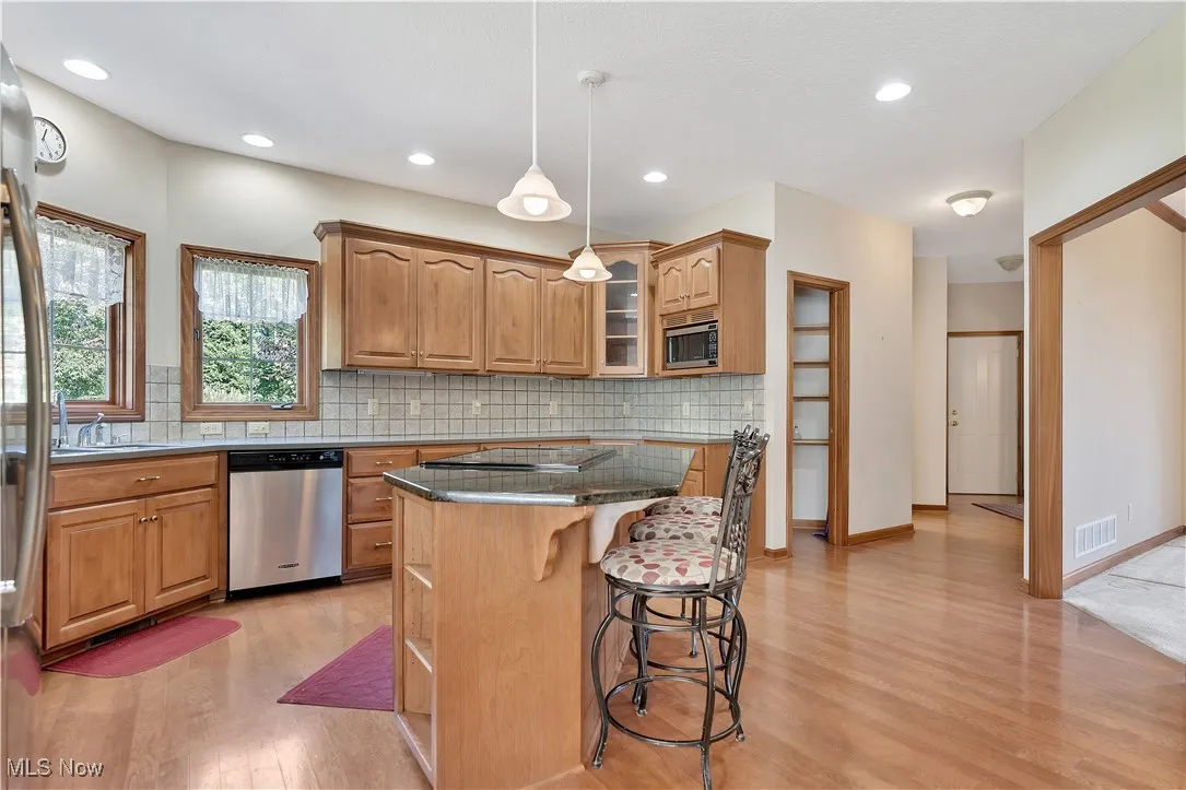 Kitchen with glass insert cabinets, a center island, backsplash, a kitchen bar, and stainless steel appliances