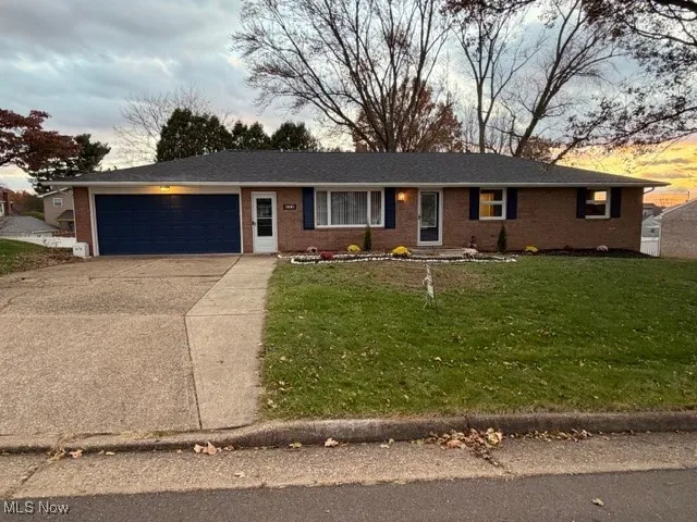 Ranch-style house featuring brick siding, a front yard, concrete driveway, and an attached garage