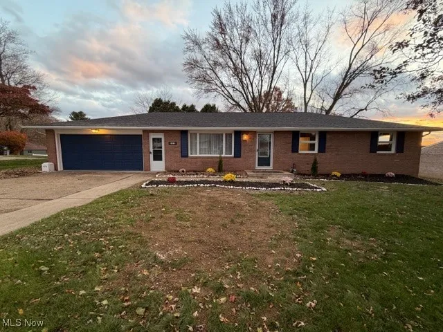 Ranch-style home featuring driveway, a yard, brick siding, and an attached garage