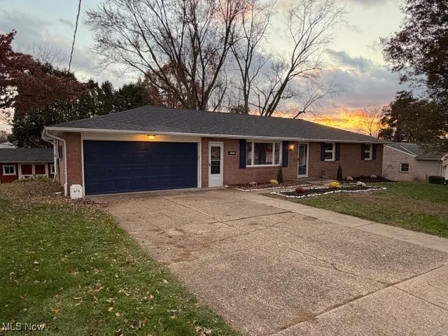 Ranch-style house featuring a front yard, concrete driveway, brick siding, and an attached garage