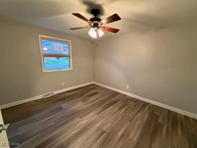 Spare room with dark wood-type flooring and ceiling fan