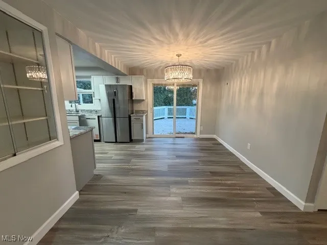 Unfurnished dining area with a chandelier and dark wood-style flooring