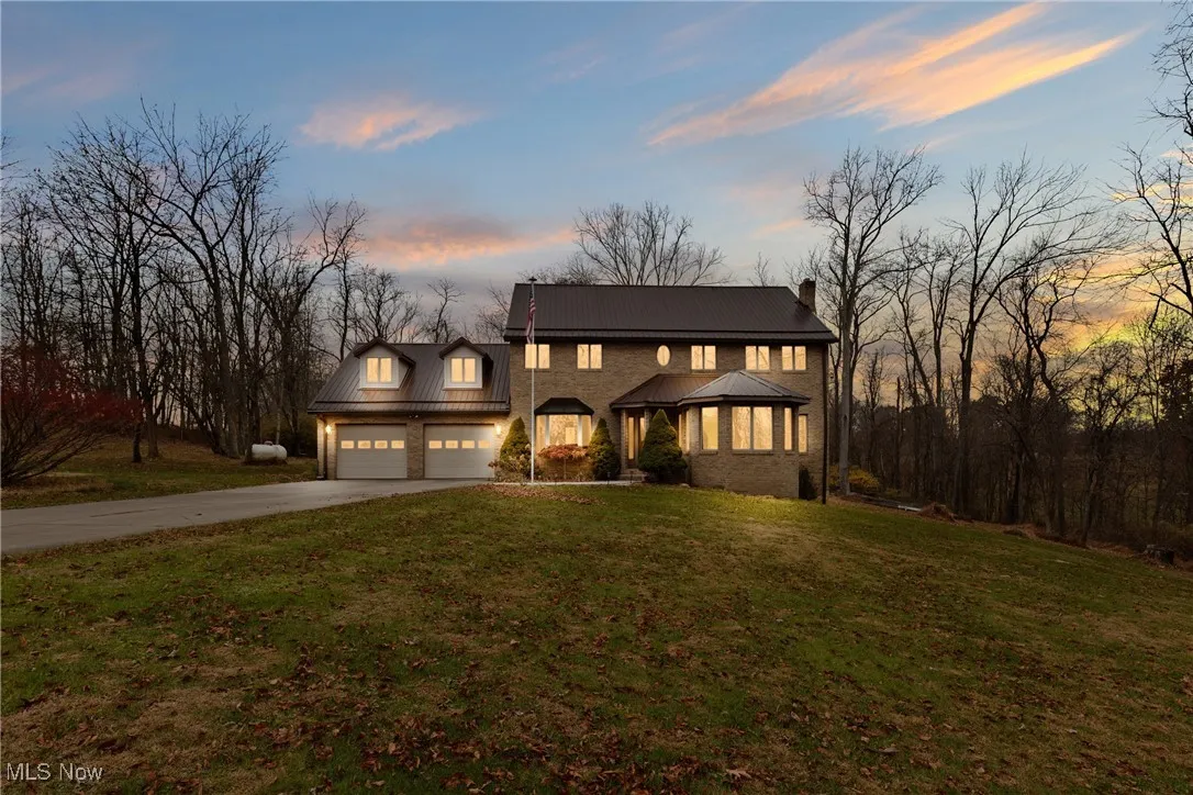 View of front of property featuring driveway, a front yard, a garage, a chimney, and a gazebo