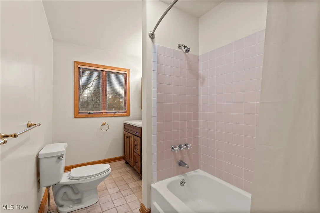 Bathroom featuring shower / bath combination with curtain, light tile patterned floors, and vanity