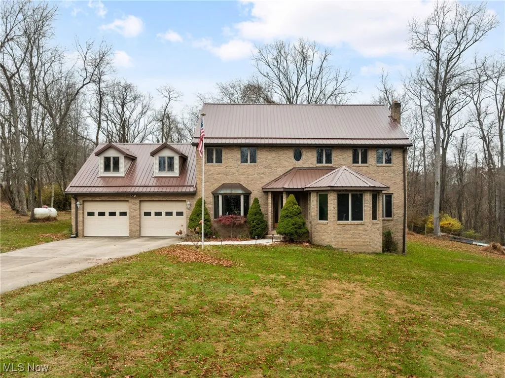 Colonial house featuring driveway, a front yard, and brick siding