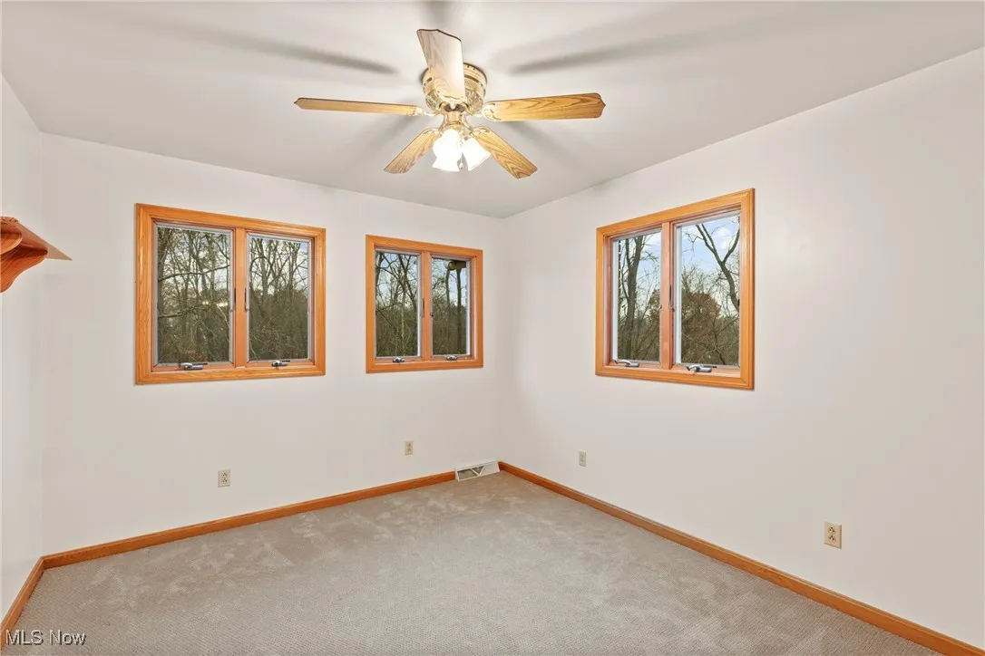 Carpeted empty room featuring a ceiling fan and baseboards