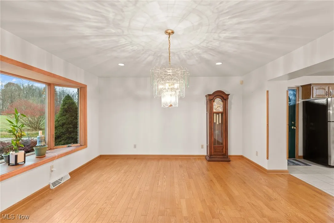 Empty room with light wood-style flooring, a chandelier, and recessed lighting