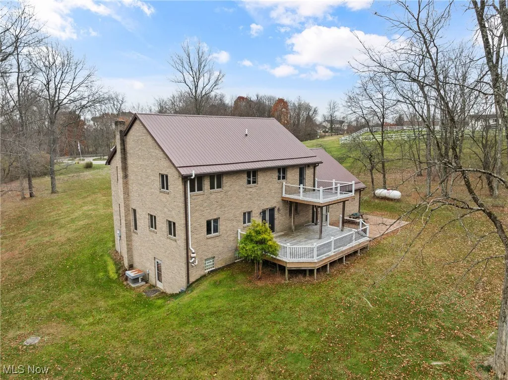 Back of property featuring a metal roof, a wooden deck, and a lawn