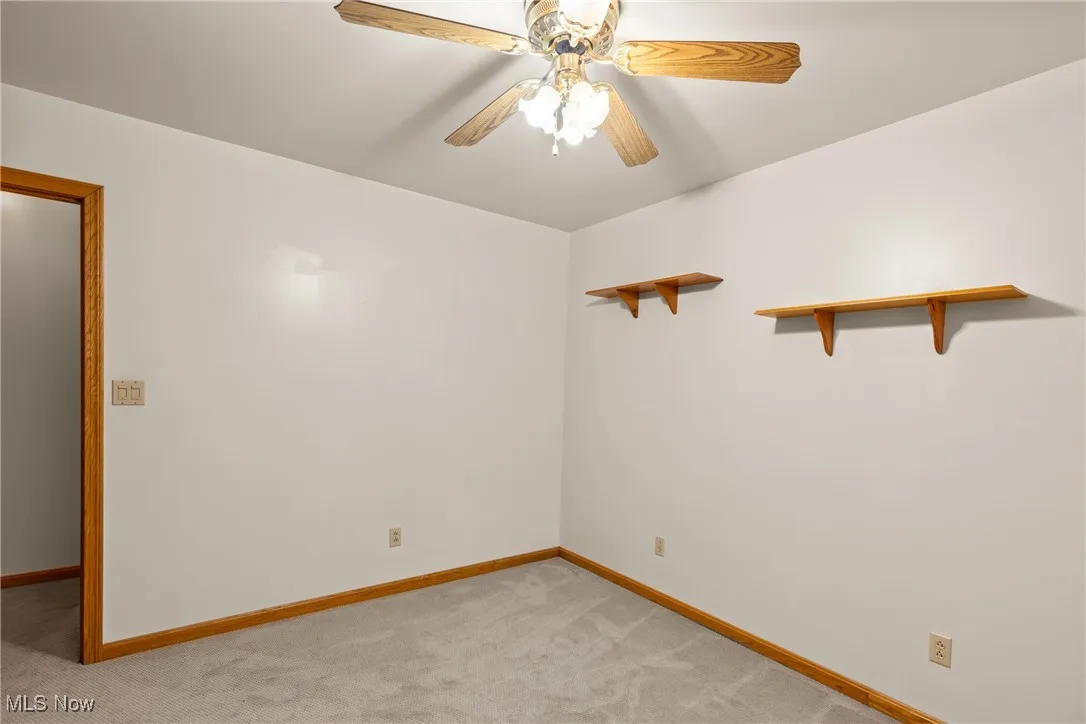Empty room featuring light carpet and a ceiling fan