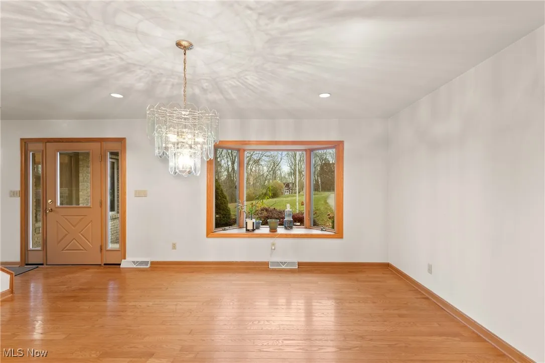 Unfurnished dining area with light wood-type flooring, recessed lighting, and a chandelier