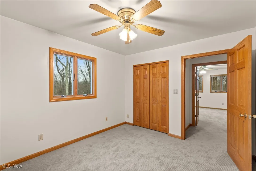 Unfurnished bedroom with light colored carpet, ceiling fan, and a closet