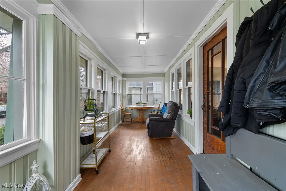 Sunroom with hardwood / wood-style floors and crown molding