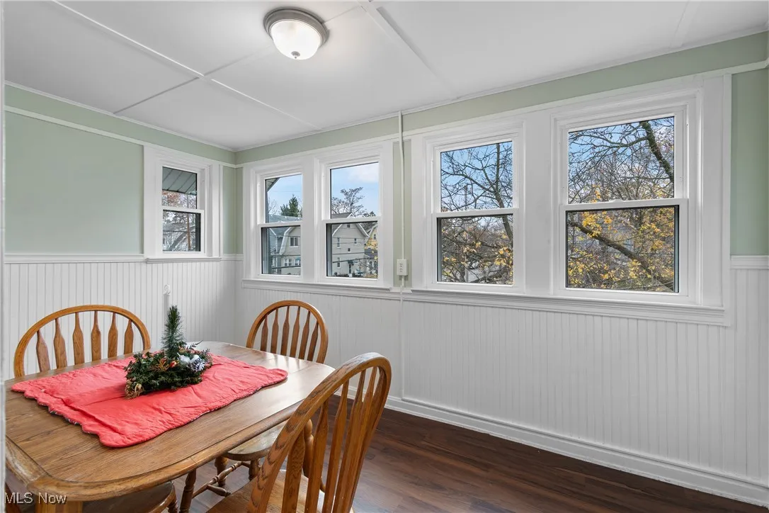 Dining area with plenty of natural light, dark wood-style floors, and wainscoting