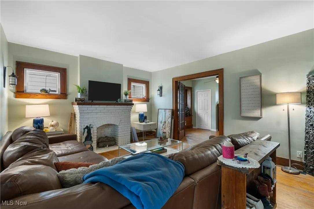 Living room with wood finished floors, a fireplace, and a ceiling fan