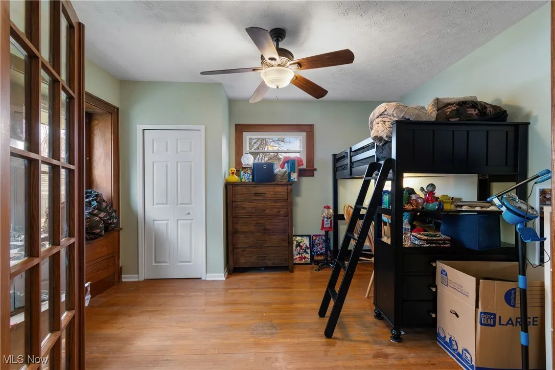 Bedroom with light wood-type flooring, a textured ceiling, and a ceiling fan