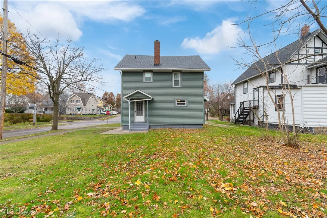 Back of house with a chimney, a lawn, a residential view, and entry steps