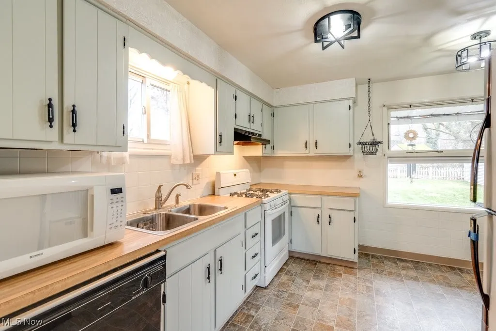 Kitchen featuring white appliances, light countertops, plenty of natural light, and tasteful backsplash