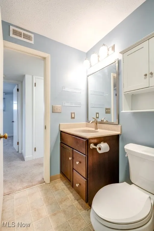 Bathroom with vanity, a textured ceiling, light tile patterned floors, and light colored carpet