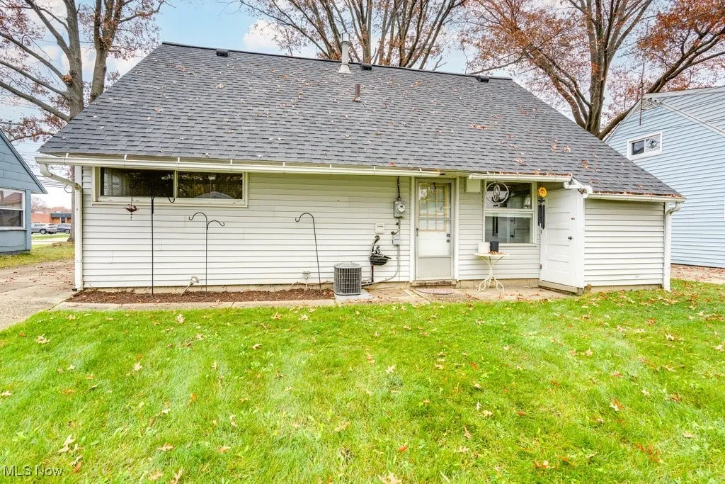 Back of property featuring roof with shingles and a lawn