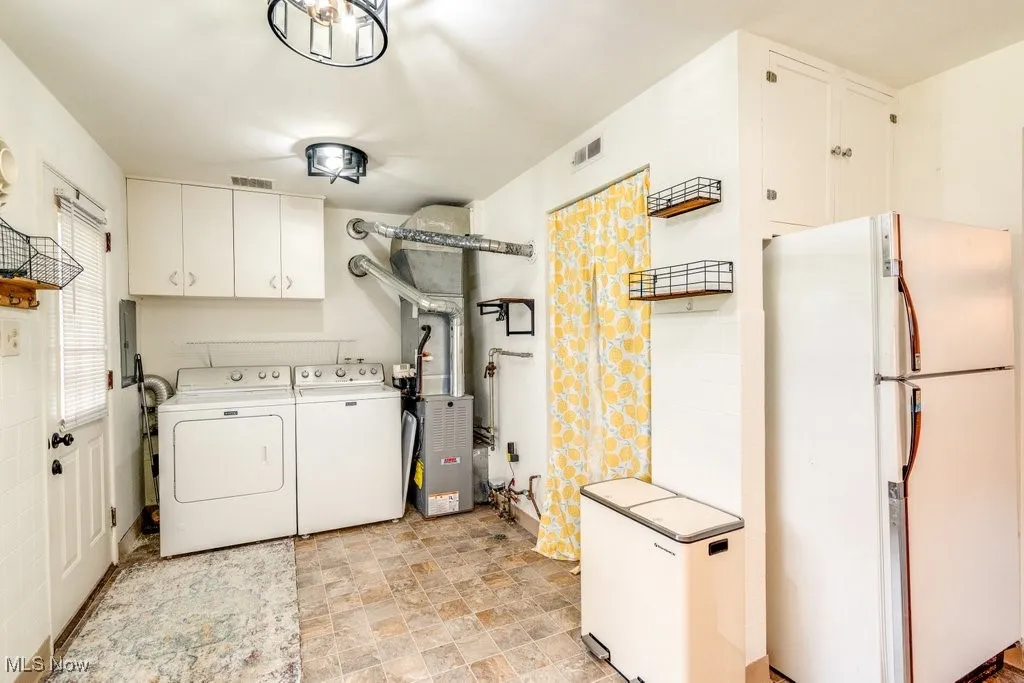 Laundry room with cabinet space, washing machine and clothes dryer, and stone finish floors