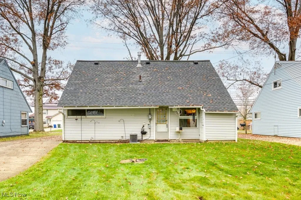 Rear view of property with roof with shingles and a lawn