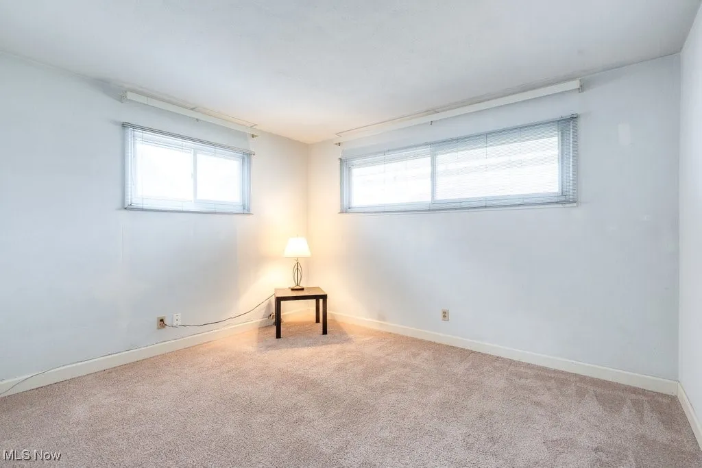 Spare room featuring light colored carpet and baseboards