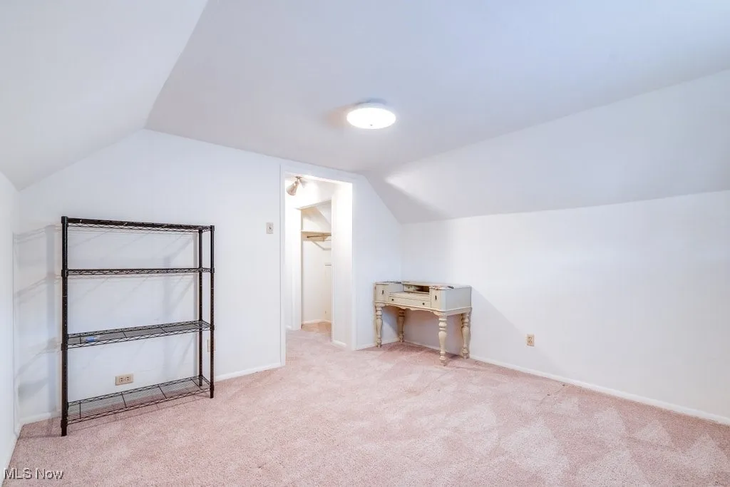 Additional living space with lofted ceiling and light carpet