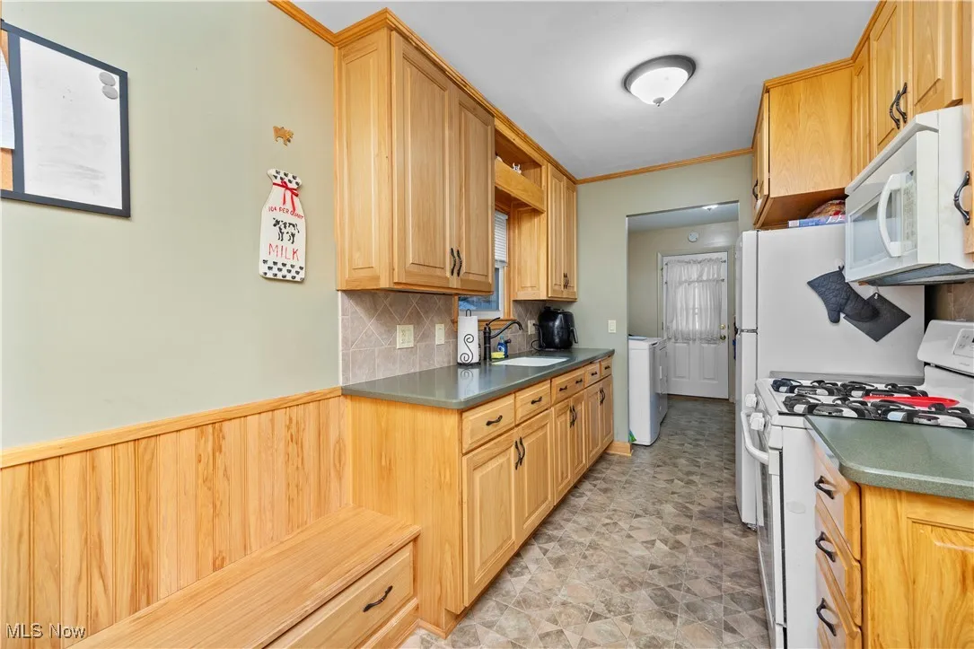 Kitchen featuring white appliances, tasteful backsplash, ornamental molding, stone finish flooring, and open shelves