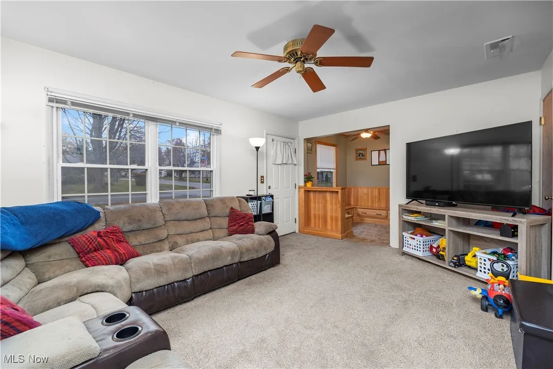 Carpeted living room with ceiling fan