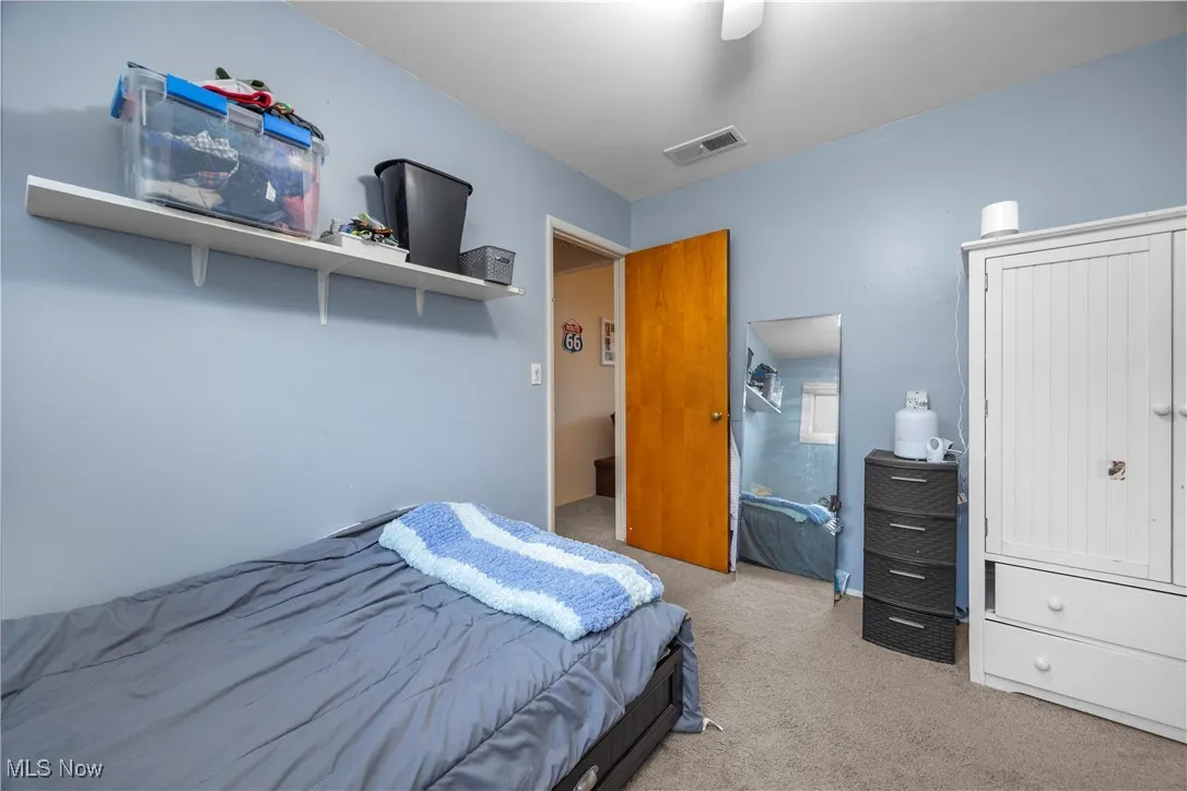 Bedroom with light colored carpet and a ceiling fan