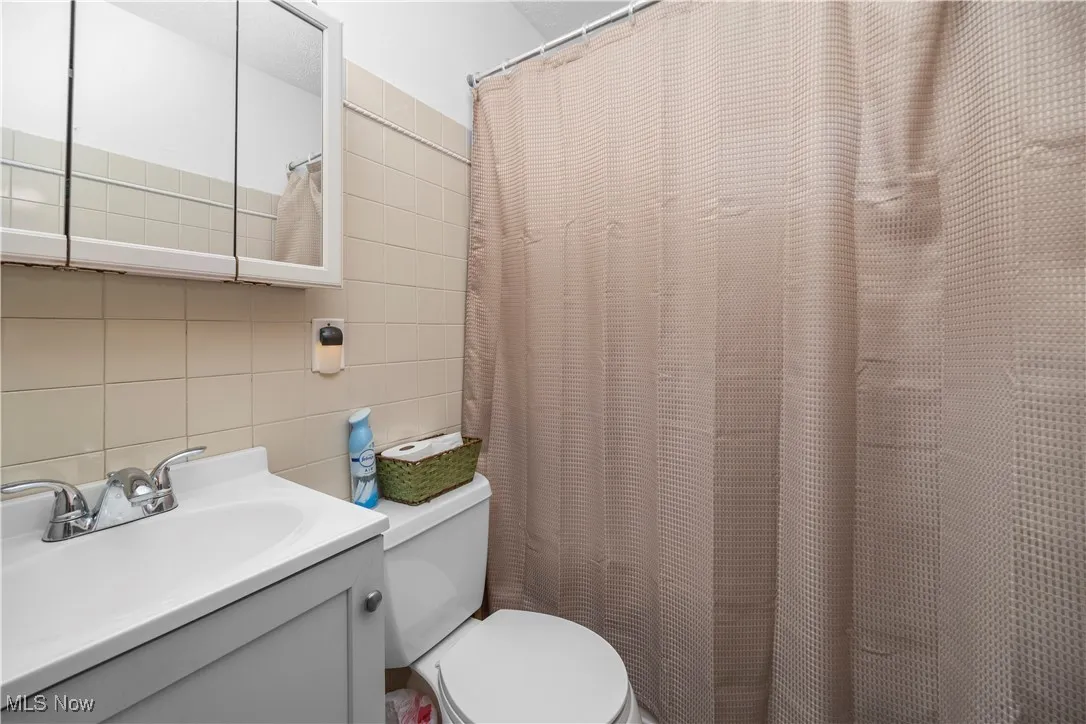 Full bathroom featuring tile walls, vanity, and curtained shower