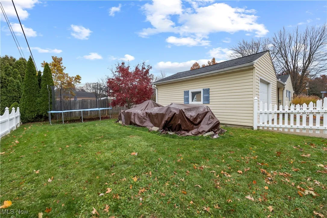Fenced backyard featuring a trampoline and a garage