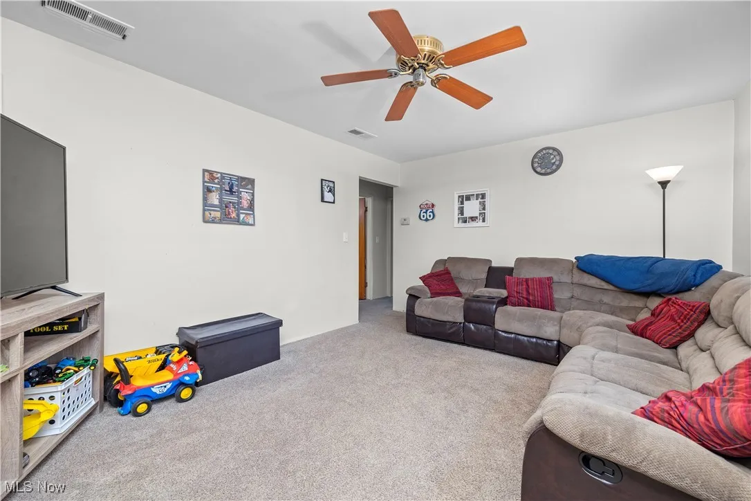 Carpeted living area with a ceiling fan
