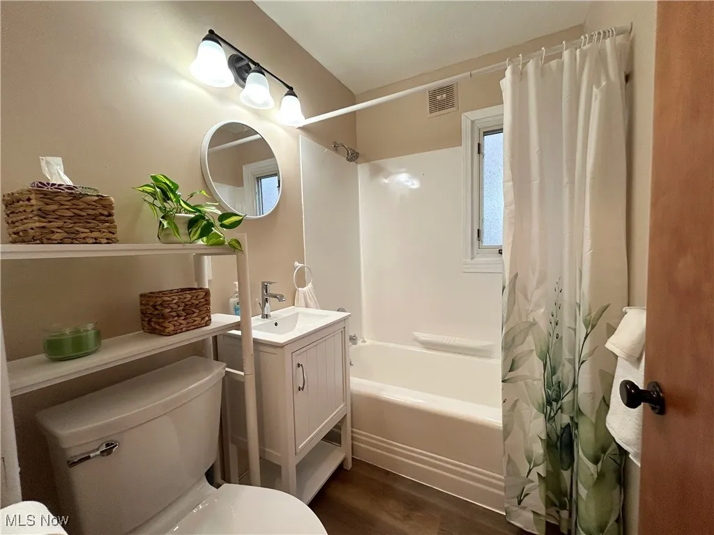 Full bath with dark wood-type flooring, shower / tub combo, and vanity